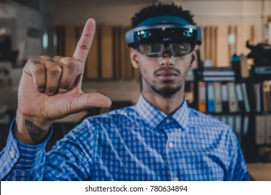 Portrait of young African American black male professional using augmented reality holographic hololens in modern office