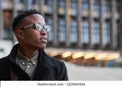 Portrait young african american businessman wearing glasses looking pensive student contemplating in city