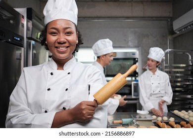 Portrait of young African American female chef in white cooking uniform looking at camera, cheerful smile with foods professional occupation, commercial pastry culinary jobs in a restaurant kitchen. - Powered by Shutterstock