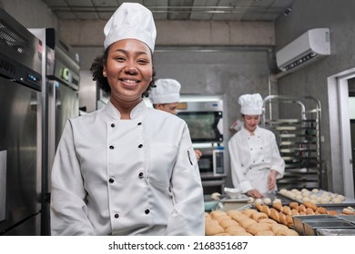 Portrait of young African American female chef in white cooking uniform looking at camera, cheerful smile with foods professional occupation, commercial pastry culinary jobs in a restaurant kitchen. - Powered by Shutterstock