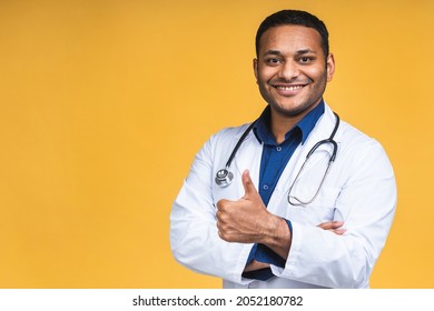 Portrait Of Young African American Indian Black Doctor With Stethoscope Over Neck In Medical Coat Standing Isolated Over Yellow Background. Thumbs Up.