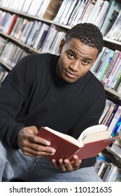 Portrait Of A Young African American Man Reading A Book In Library