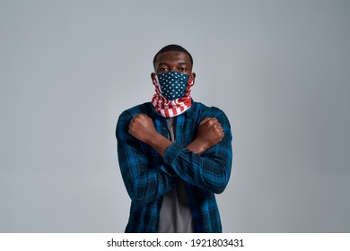 Portrait Of Young African American Man Wearing Bandana Mask Showing Cross Gesture Protesting For Human Rights, Looking At Camera While Posing Isolated Over Gray Background. Social Issues Concept