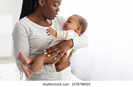 Portrait Of Young African American Mother Holding Her Crying Baby On Hands. Displeased Irritated Hungry Infant Whining, Feeling Pain Or Colic. Free Copy Space, White Background. Motherhood Concept