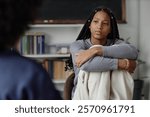 Portrait of young African American teenage girl listening to therapist or school counsellor during one on one meeting copy space