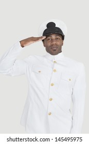 Portrait Of A Young African American US Navy Officer Saluting Over Gray Background