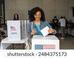 portrait of a young african american woman voting in the us election, placing vote ballot in the polling box, vote in America. Concept of choice, democracy and freedom