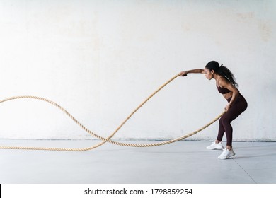 Portrait Of Young African American Woman Doing Workout With Battle Rope In Bright Room