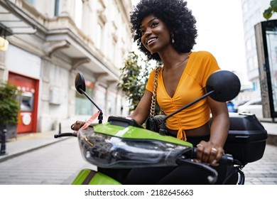 Portrait of young african american woman riding green motorbike in the city - Powered by Shutterstock