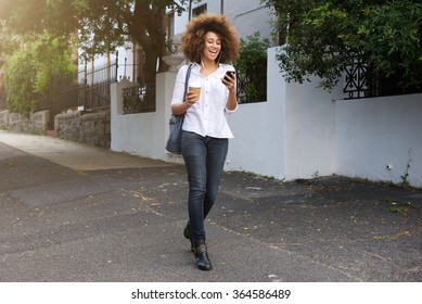 Portrait Of Young African American Woman Walking And Looking At Cellphone