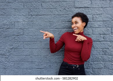 Portrait of young african american woman smiling and pointing finger at copy space