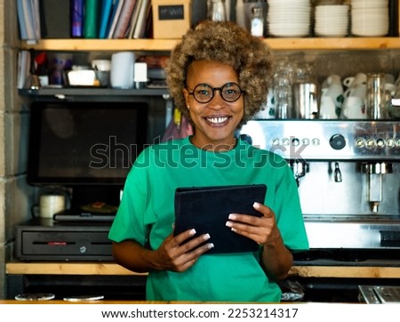 Portrait of a young African American woman wih a tablet looking at camera in a pub. Entrepreneurial woman, small business
