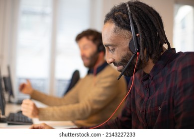 Portrait of a young African or Caribbean office worker, customer service operator or tele consultant in communication or remote meeting with his headset on his head