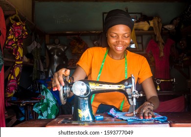 portrait of a young african female tailor smiling while working with her sewing machine - Powered by Shutterstock