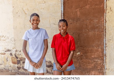 portrait young african girls with braids in the village, house in the background