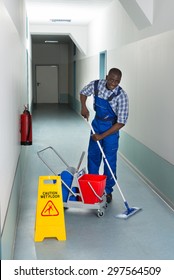 Portrait Of Young African Male Janitor Cleaning Floor In Corridor
