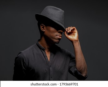 Portrait Of A Young African Man In A Black Hat. Black Background Studio Photography