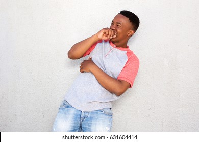 Portrait Of Young African Man Laughing With Hand Over Mouth Against White Background