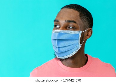 Portrait Of A Young African Man Wearing Mask For Coronavirus Looking To Side, Against Blue Studio Background