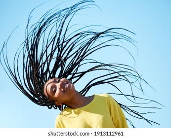 portrait of a young african woman with long hair and dreadlocks, looking happy and cheerful, isolated outdoors - Powered by Shutterstock