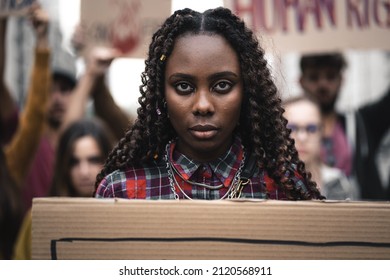 Portrait of a young African woman marching during a youth protest - face detail, other remonstrants behind - concept of young people protesting against politics or fighting for human rights