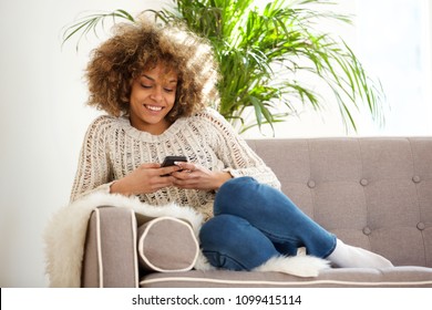 Portrait Of Young African Woman Relaxing At Home And Using Mobile Phone