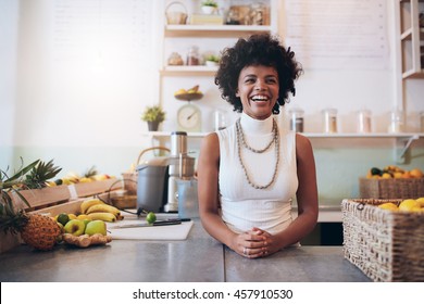 Portrait of young african woman standing behind juice bar counter looking at camera and smiling. Happy juice bar owner. - Powered by Shutterstock