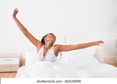 Portrait Of A Young African Woman Stretching Her Arms On Bed