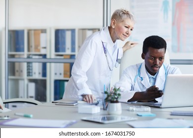 Portrait Of Young African-American Doctor Using Laptop With Senior Supervisor Looking Over Shoulder, Copy Space