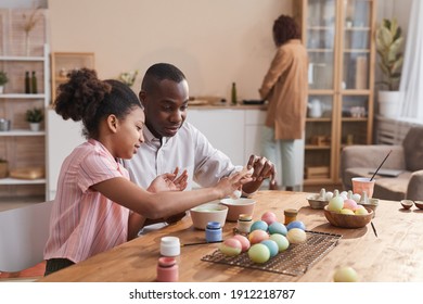 Portrait of young African-American girl painting Easter eggs while enjoying DIY decorating with loving father, copy space - Powered by Shutterstock