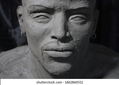 
Portrait of the young African-American man. Statue in process of creation. Handmade sculpture in clay on black background.
