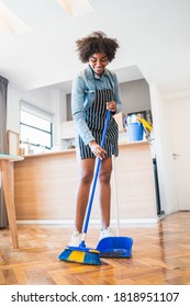 Portrait Of Young Afro Woman Sweeping Wooden Floor With Broom At Home. Cleaning, Housework And Housekeeping Concept.