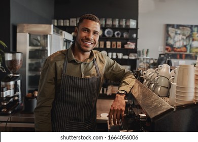 Portrait of young afro-american male business owner behind the counter of a coffee shop smiling looking at camera - Shutterstock ID 1664056006