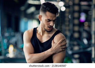 Portrait Of Young Arab Man With Shoulder Pain Suffering Sport Injury During Training At Gym, Middle Eastern Male Athlete Having Trauma After Fitness Workout, Rubbing Painful Area, Closeup - Powered by Shutterstock