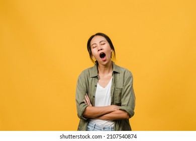 Portrait of Young Asia lady with negative expression, bored yawning tired covering mouth with hand in casual clothing isolated on yellow background with blank copy space. Facial expression concept - Shutterstock ID 2107540874
