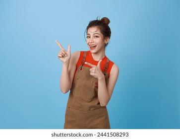 Portrait young asian barista woman wearing apron standing and pointing fingers isolated on blue background, waitress or entrepreneur cheerful, small business or startup, - Powered by Shutterstock