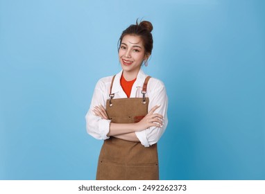 Portrait young asian barista woman wearing apron standing and smile arms crossed isolated on blue background, waitress or entrepreneur cheerful, small business or startup, - Powered by Shutterstock