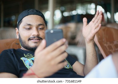 A Portrait Of A Young Asian Boy Busy Attending A Video Call On His Smart Phone