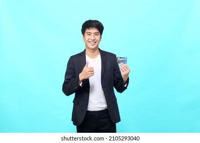 Portrait of young Asian businessman Holding and showing credit card on hand on Isolated blue background - Powered by Shutterstock