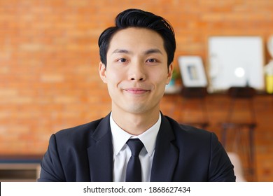 Portrait Young Asian Businessman Talking On Video Call Or Virtual Meeting In Office, Front View, Look At Camera