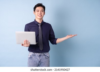 Portrait Of Young Asian Businessman Using Laptop On Blue Background