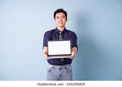 Portrait Of Young Asian Businessman Using Laptop On Blue Background