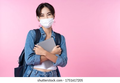 Portrait Of Young Asian College Student Wears Face Mask With Laptop And Backpack Isolated Over Pink Background