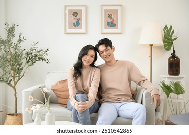 Portrait of young asian couple sitting in living room at home - Powered by Shutterstock