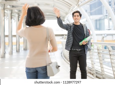 Portrait Of A Young Asian Couple Of University Students Say Hello Greeting On The Street