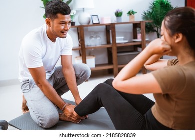 Portrait Of Young Asian Couple Workout Sit Up Together At Home Stretching Their Body