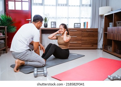 Portrait Of Young Asian Couple Workout Sit Up Together At Home Stretching Their Body