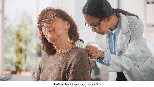 Portrait of a Young Asian Dermatologist Using a Medical Magnifying Glass to Inspect any Damages on the Skin of a Senior Patient During a Health Check Visit to a Clinic. Doctor Working in Hospital - Powered by Shutterstock