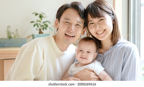 Portrait Of Young Asian Family With Baby Relaxing In The Living Room