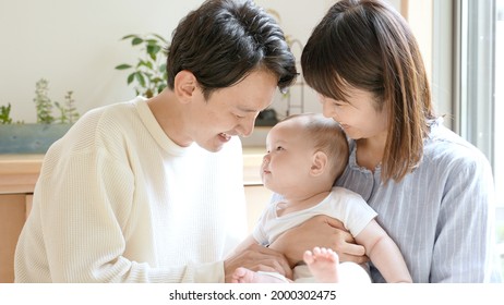 Portrait Of Young Asian Family With Baby Relaxing In The Living Room